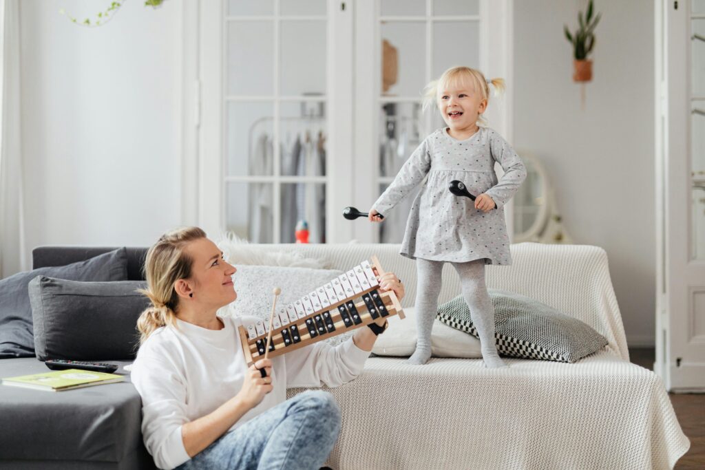A joyful family playing music together in a cozy living room, with a child on the keyboard and parents clapping and smiling.

