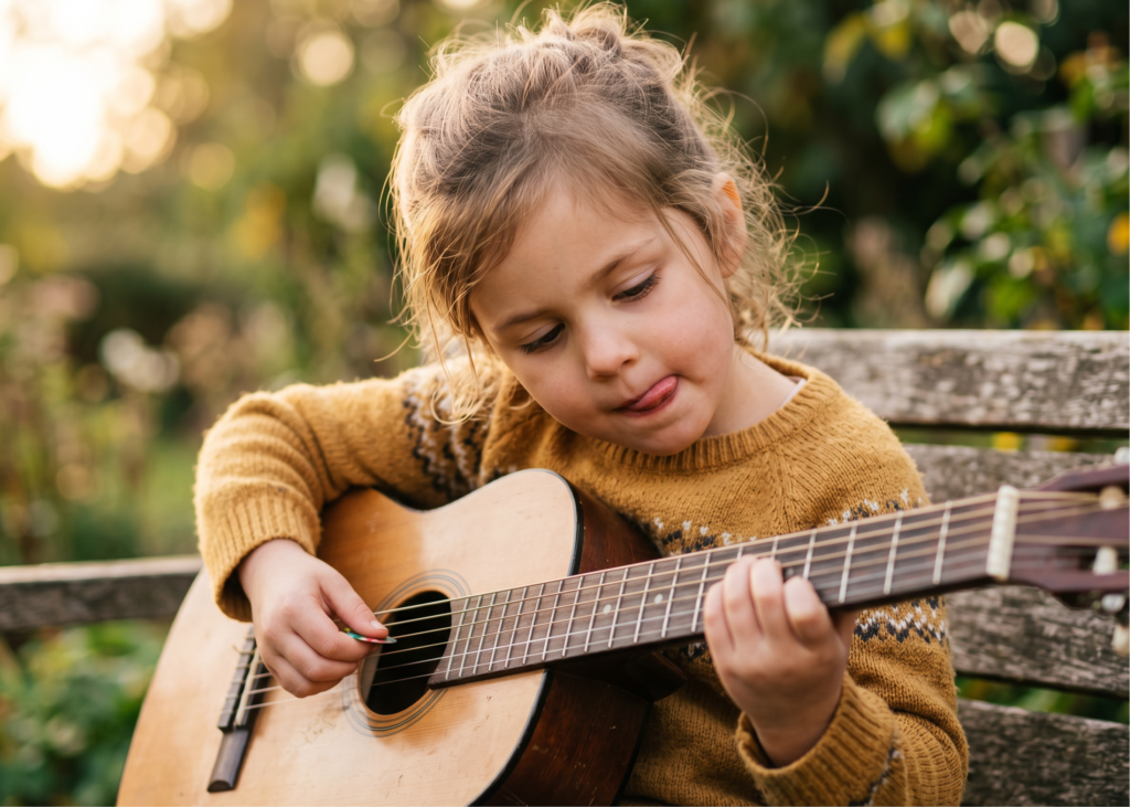 Young girl learning guitar outdoors, enjoying music lessons for kids in Noosa

