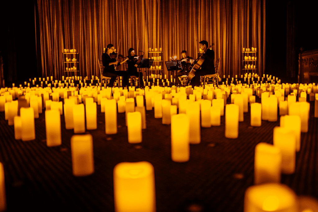 Candlelit outdoor concert setting with orchestral musicians performing at Flaxton Gardens